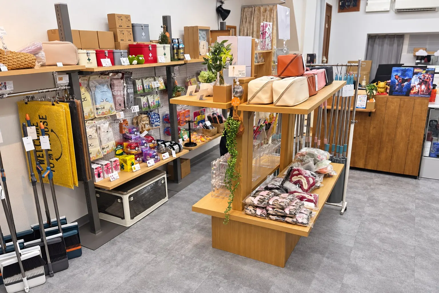 MILGRAIN の店内。雑貨が並ぶ壁の棚と有孔ボード、ポーチや観葉植物を置いた中央の台
